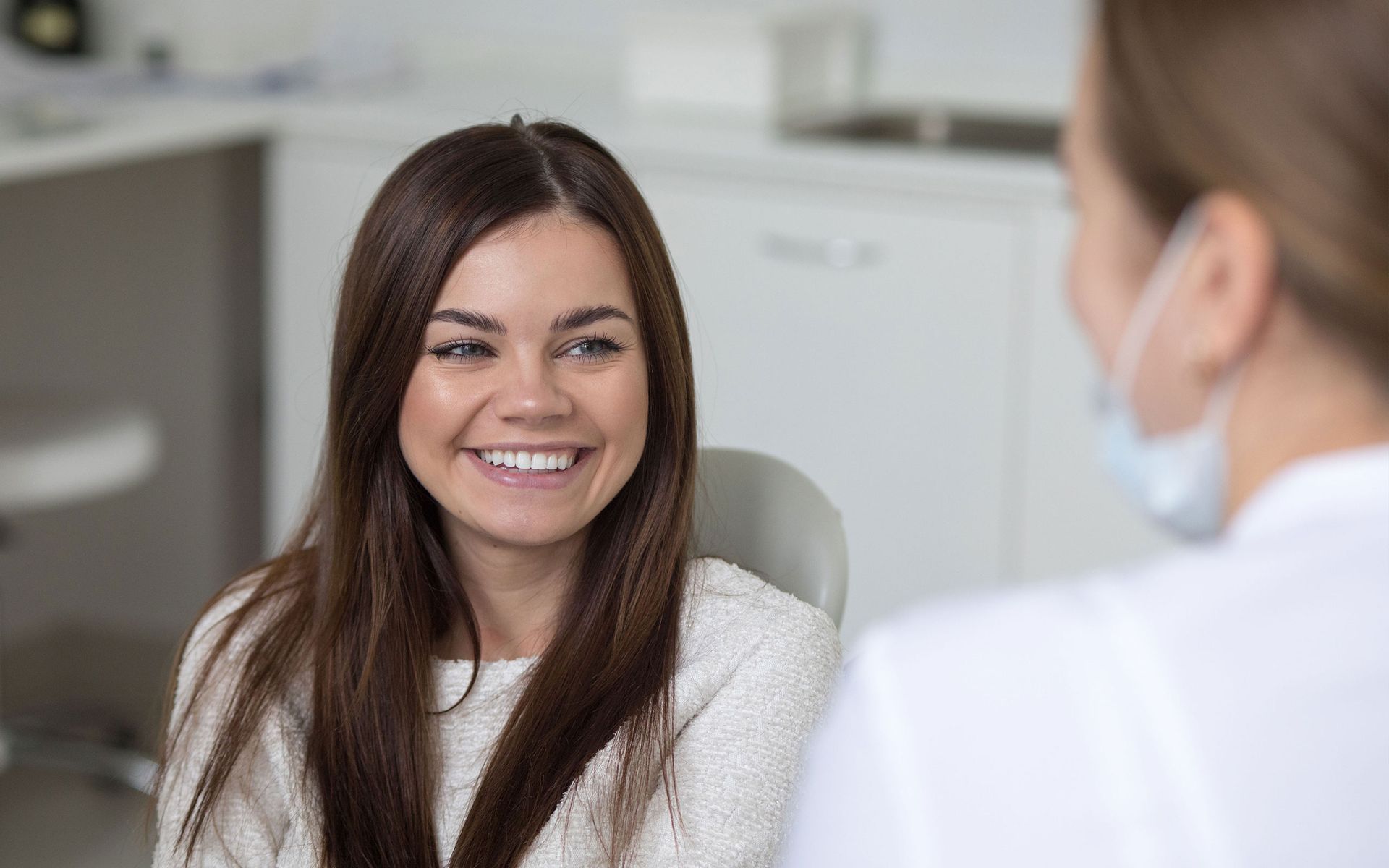 a woman is smiling while talking to a dentist in a dental office