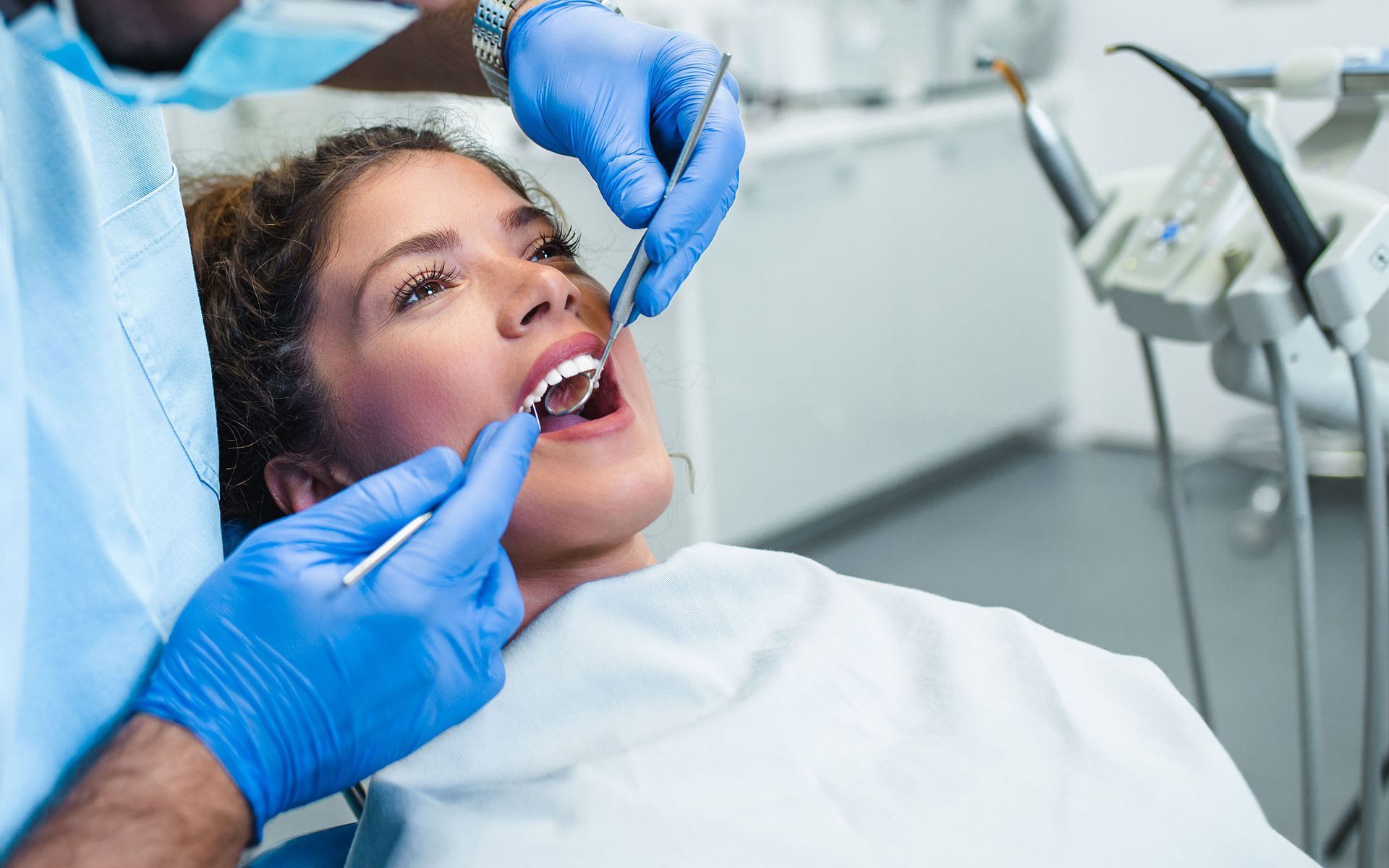 a woman is sitting in a dental chair getting her teeth examined by a dentist