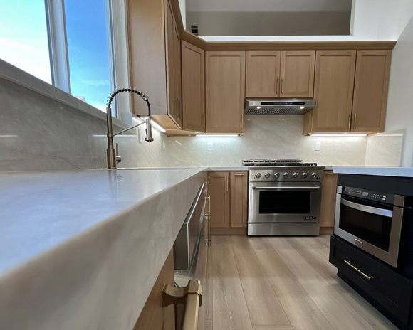 Modern living room with wood floors, neutral tones, and a view into the dining area.