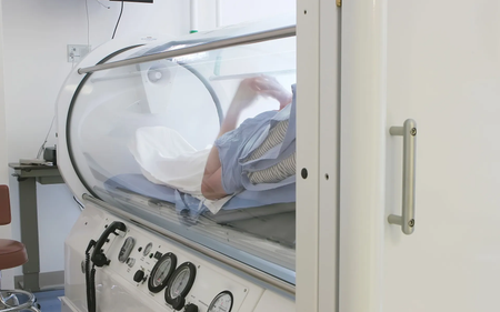 A man is laying in an oxygen chamber in a hospital.