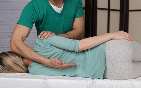 A woman is laying on a table getting a massage from a man.
