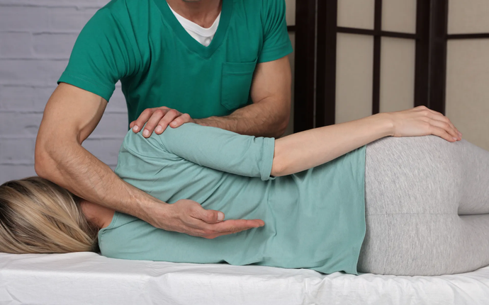 A woman is lying on a bed getting therapy from a man.