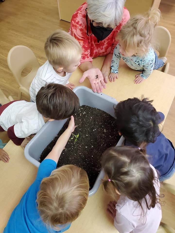 Child's hand playing with colorful building blocks, stacking them on a white surface.