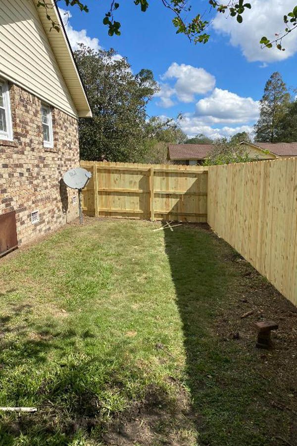 A wooden fence is in the backyard of a house.