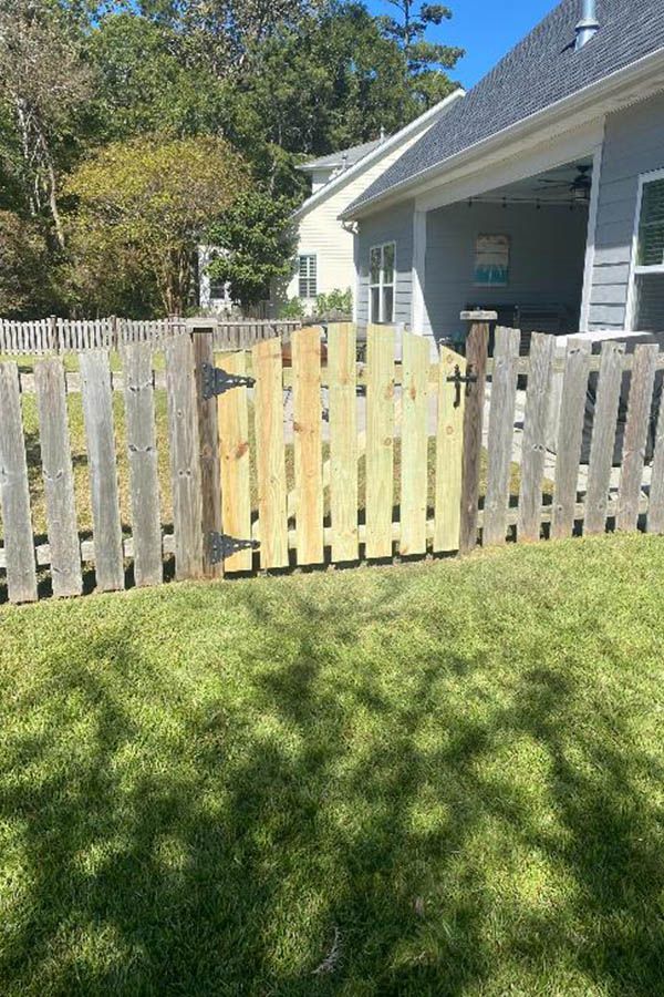 A wooden fence with a gate in the backyard of a house.