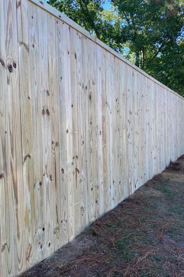 A long wooden fence is sitting on top of a grassy field.