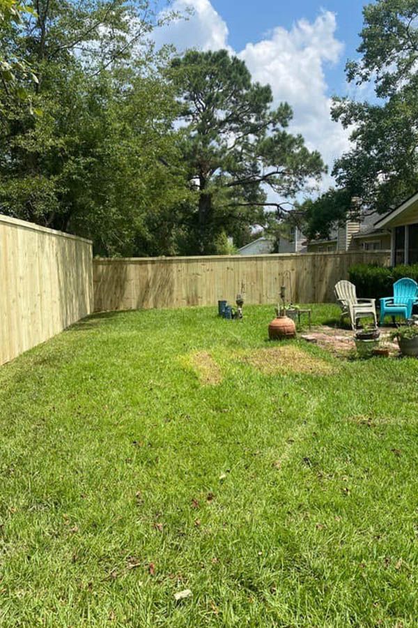 A backyard with a wooden fence and a fire pit.