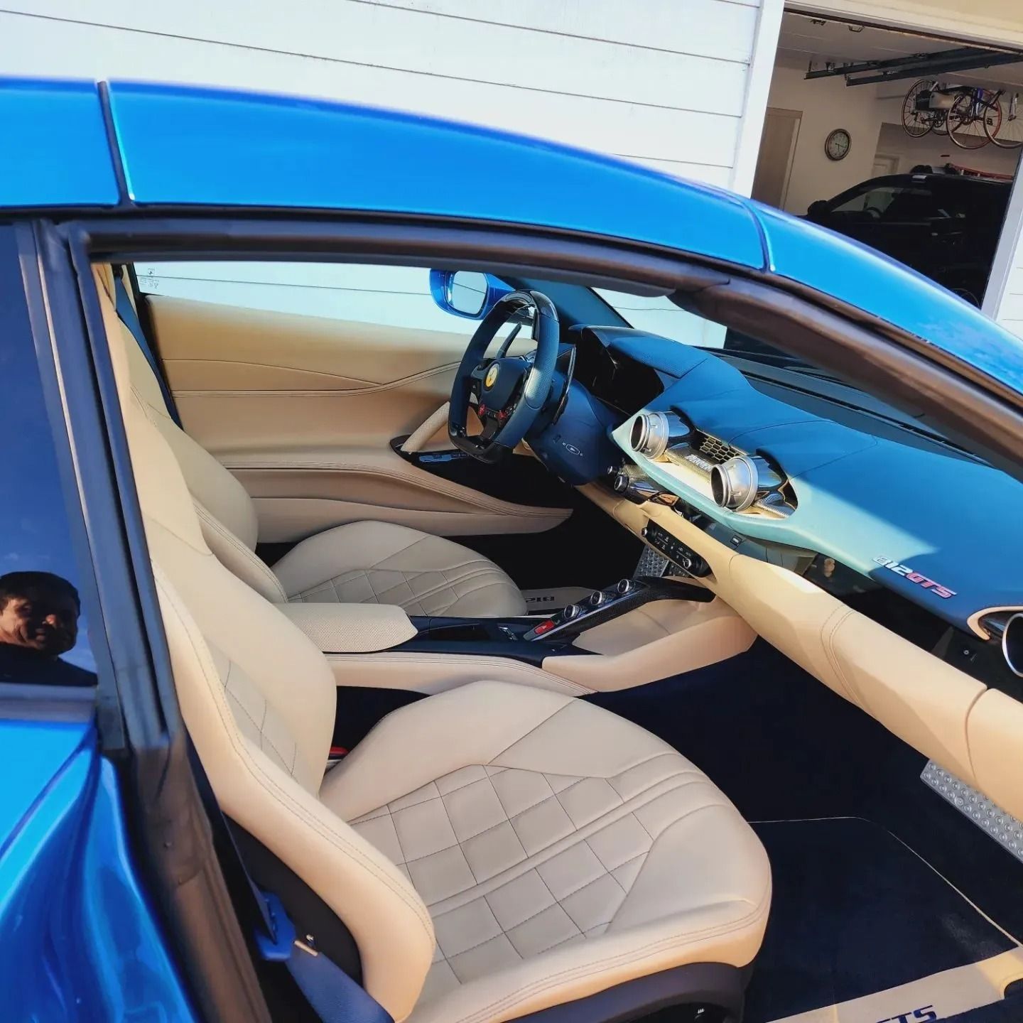 Interior of a blue sports car featuring beige quilted leather seats, a steering wheel, and a modern dashboard.