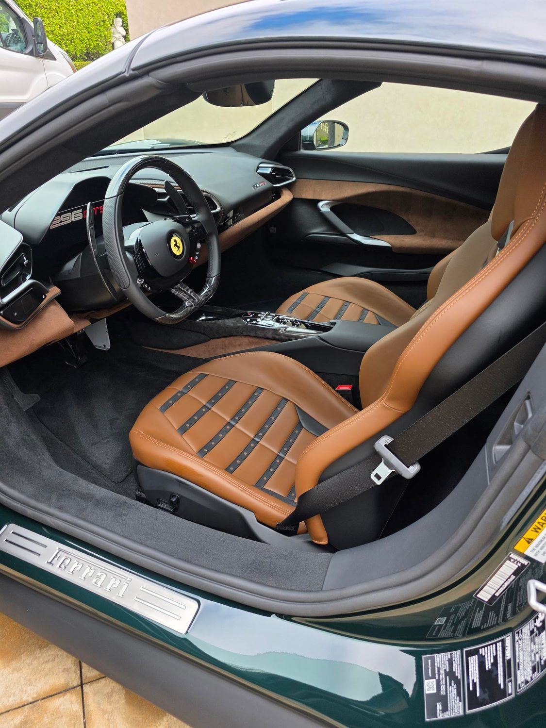 Green Ferrari interior with tan leather seats and black accents, viewed through the open driver door