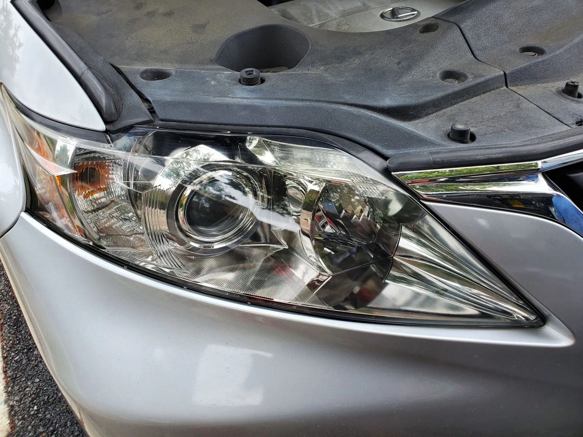 Close-up of a silver car's headlight assembly with a visible crack across the clear plastic lens.