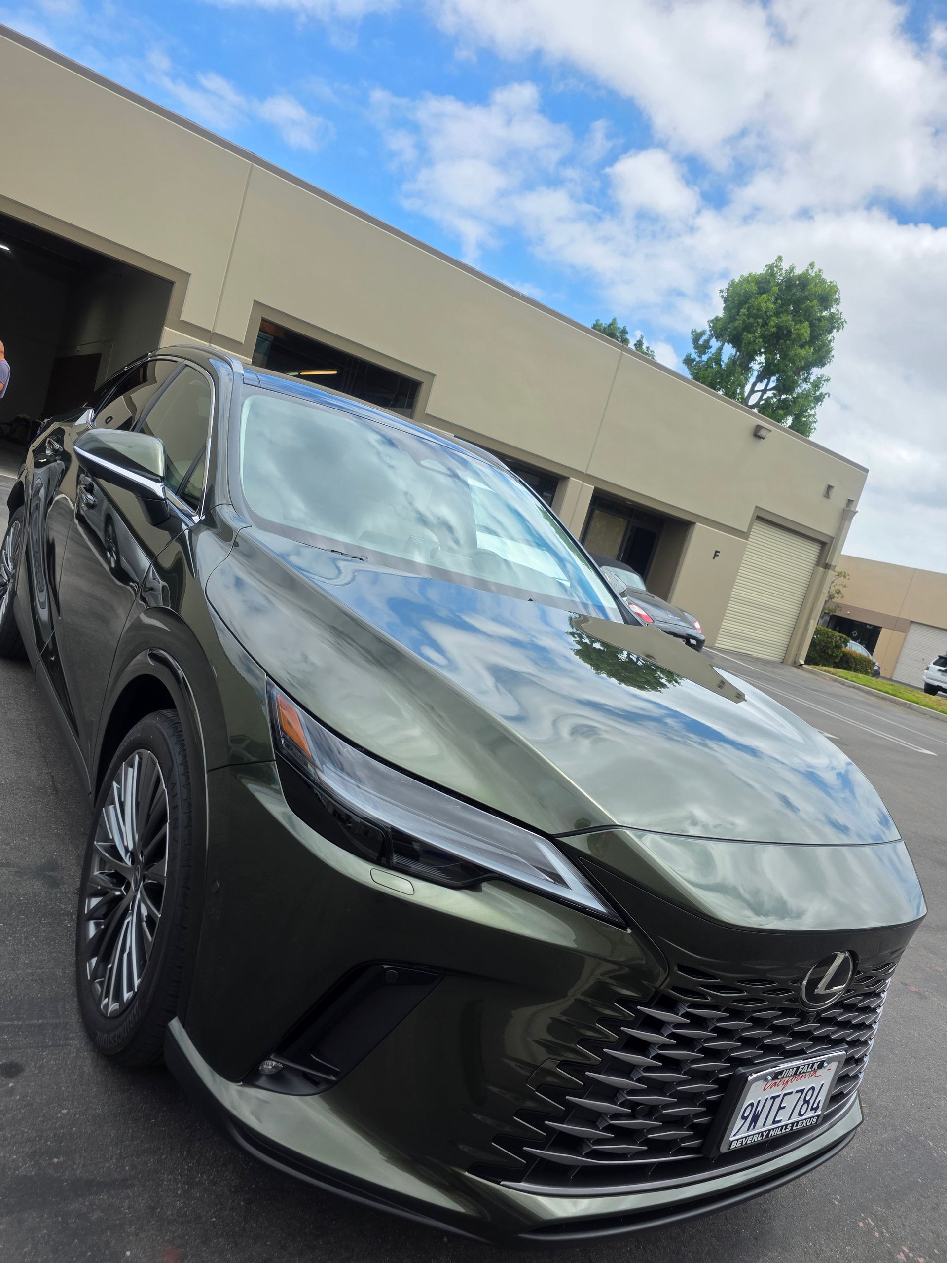 Dark green SUV parked outside a beige building under a partly cloudy sky