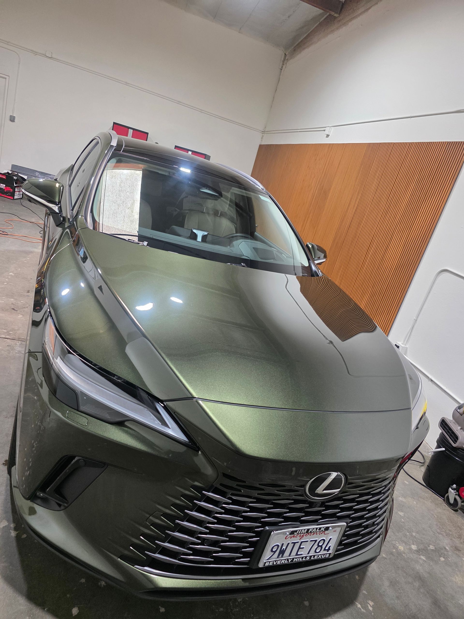 Olive green Lexus SUV parked in a garage, front view.