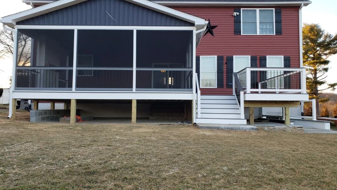 Two-story house with screened porch, wooden deck, red siding, and a grassy yard.