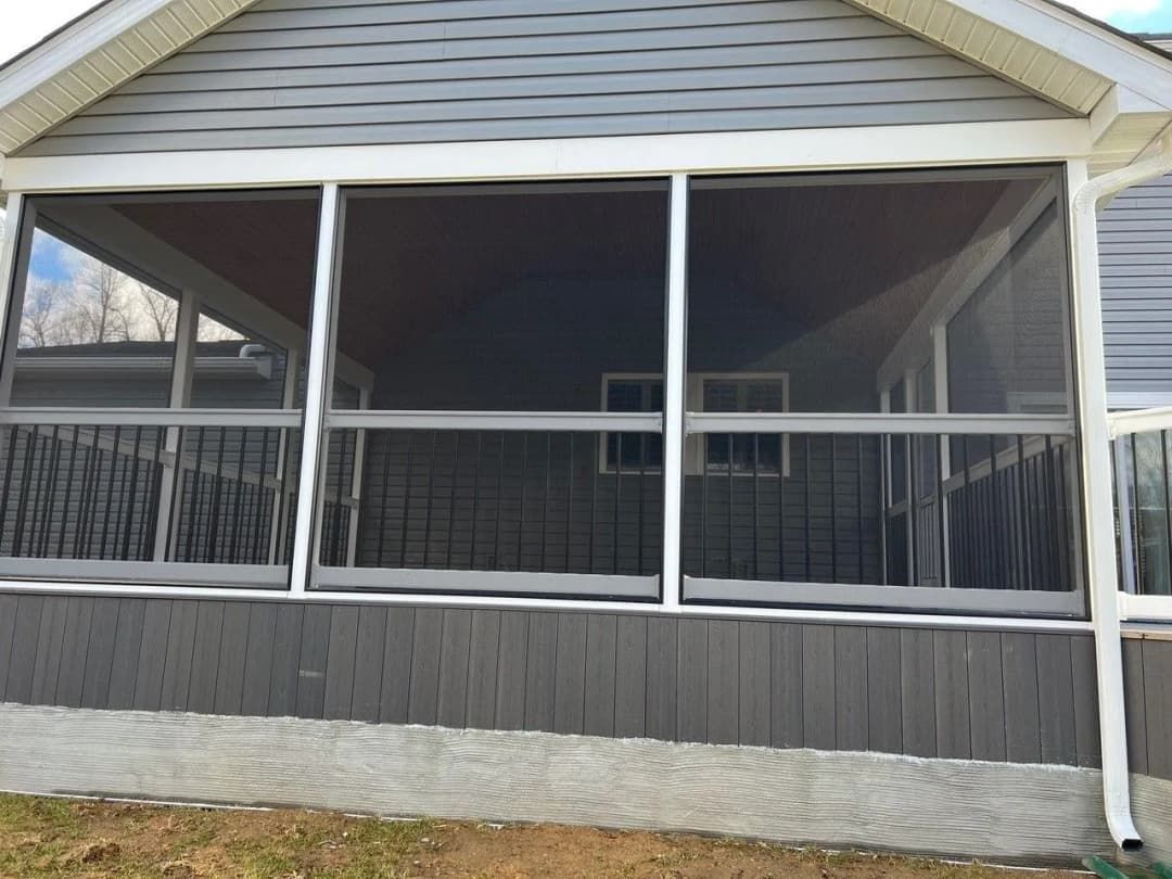 Screened-in porch with gray siding and white trim. Three large screened panels span the view.