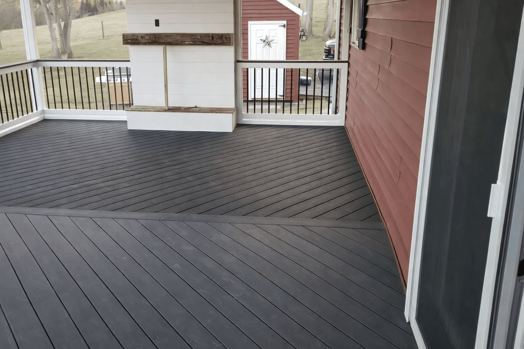 Gray composite deck with a white railing. Red siding and a screen door are on the right.