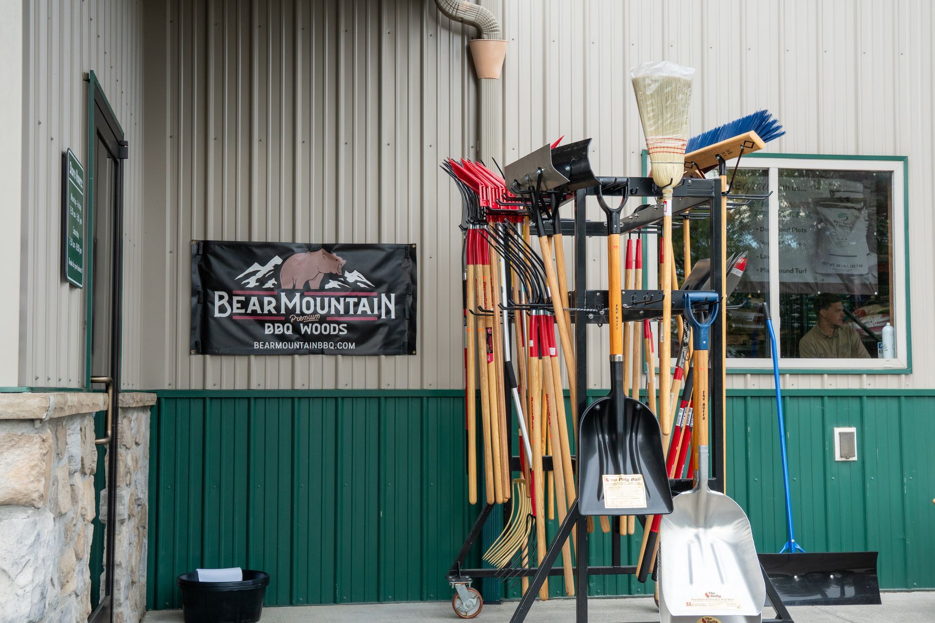 Tools stand by a building with a Bear Mountain Ski Area banner and a window reflecting a person.