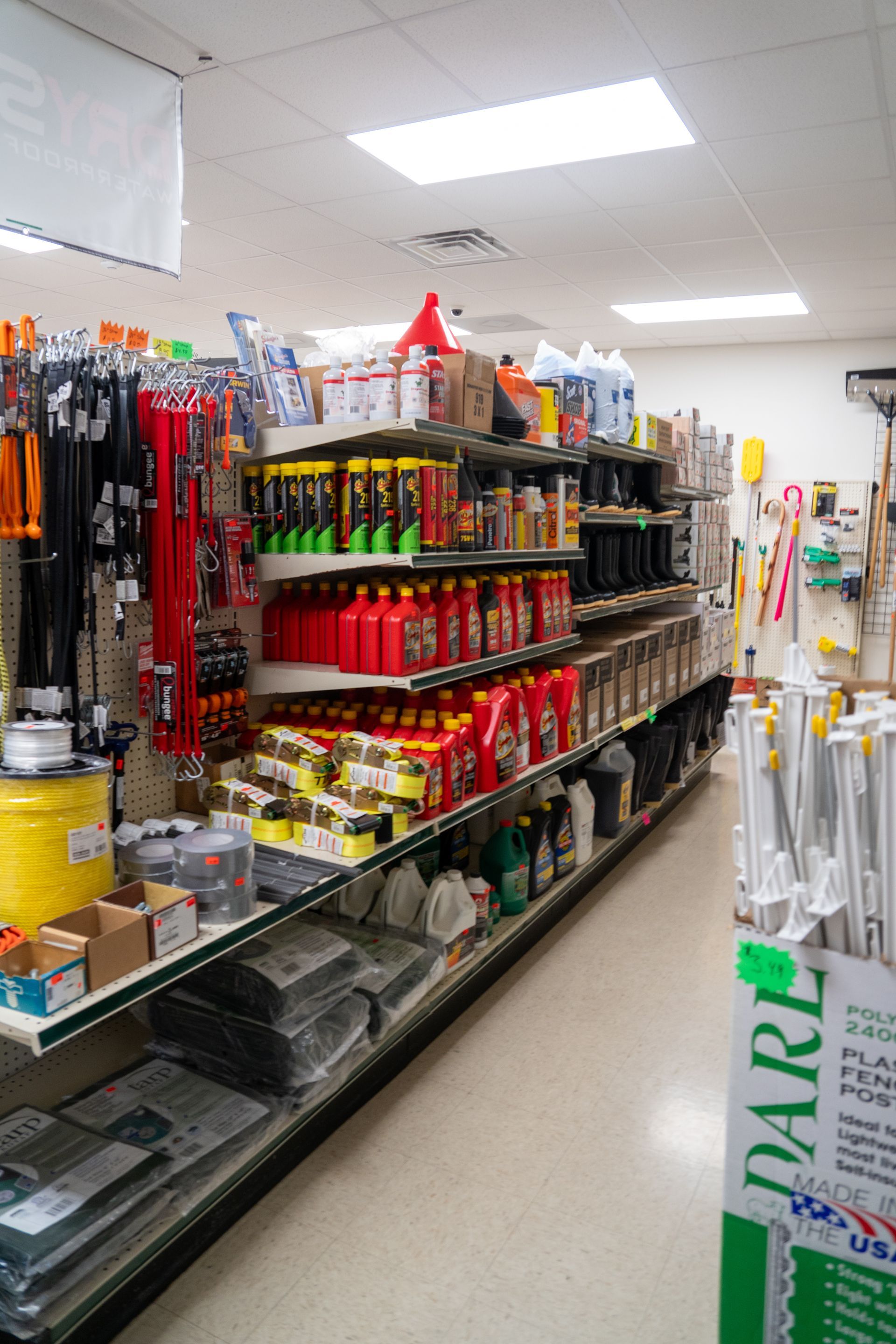 Shelves stocked with hardware store items, including tools, fluids, and supplies.