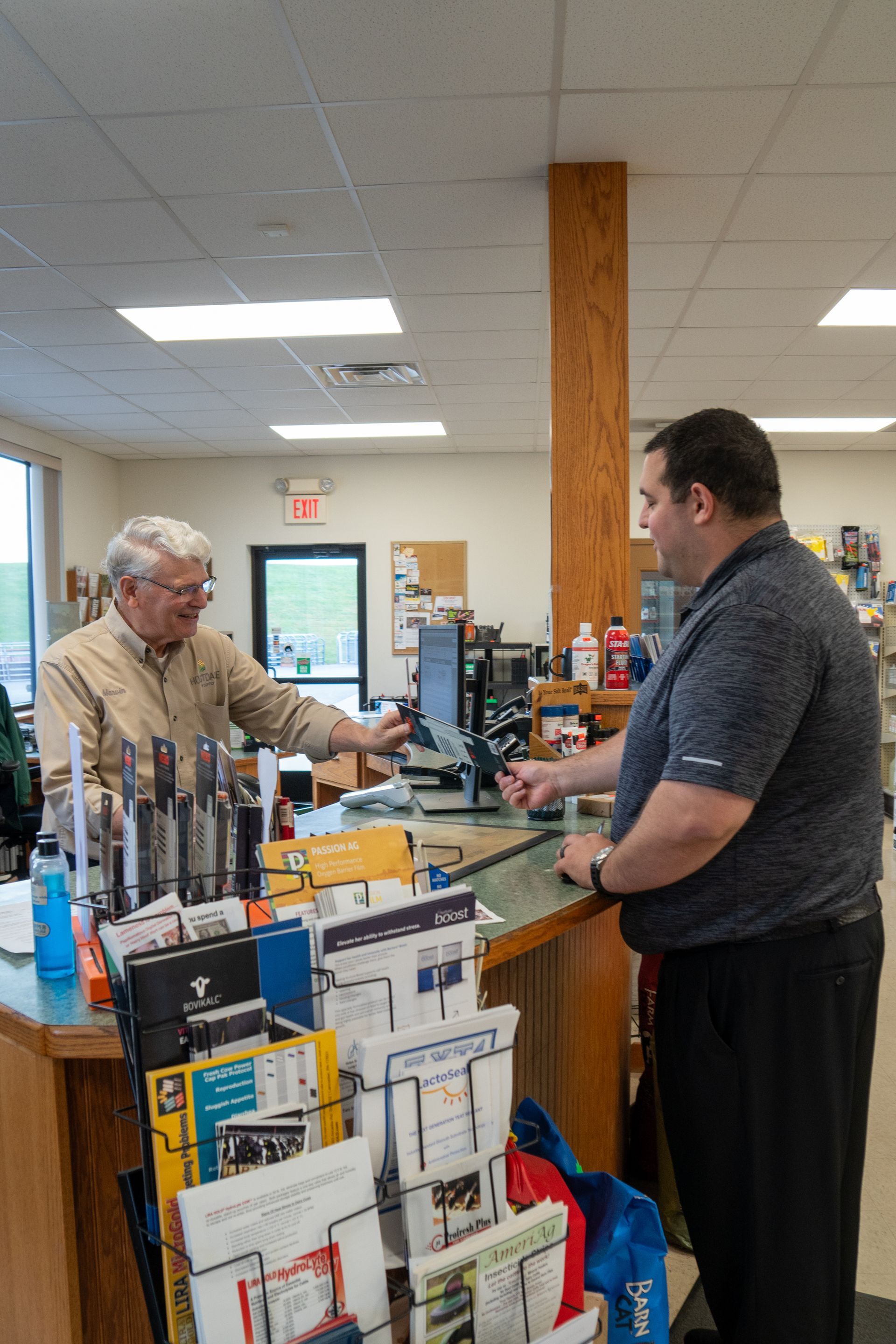 Man and clerk at a counter, possibly in a store, both looking at computer screen.