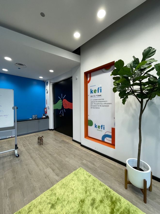 Office interior with a green rug, fiddle-leaf fig, and a sign that says Kefi.