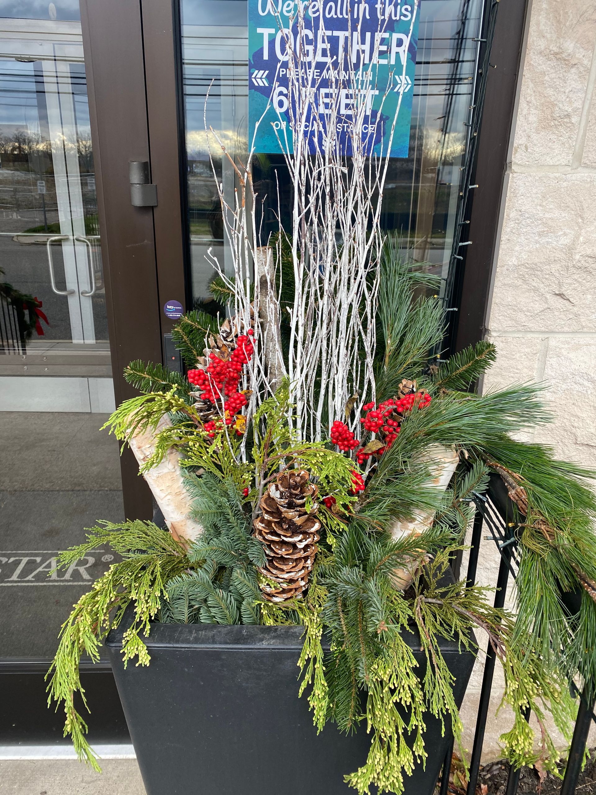 A planter with christmas decorations is in front of a building.
