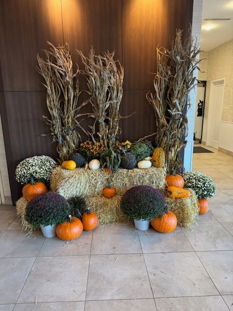 A display of pumpkins , flowers and hay bales in a hallway.