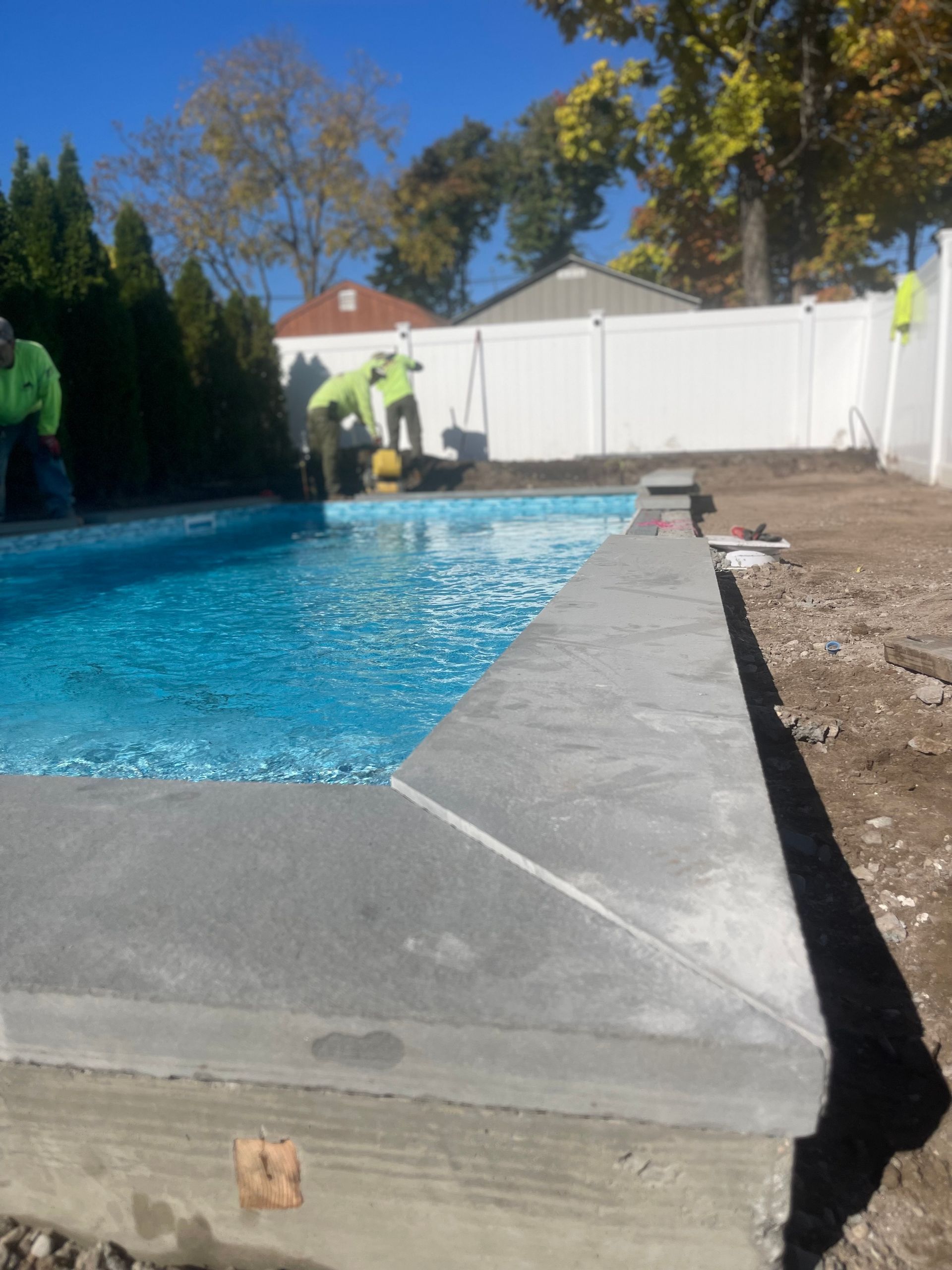 A swimming pool with a white fence in the background