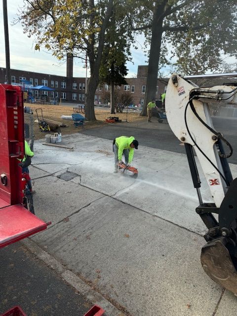 A man is working on a sidewalk next to a bulldozer