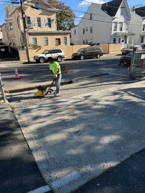 A man is using a vacuum cleaner to clean the sidewalk