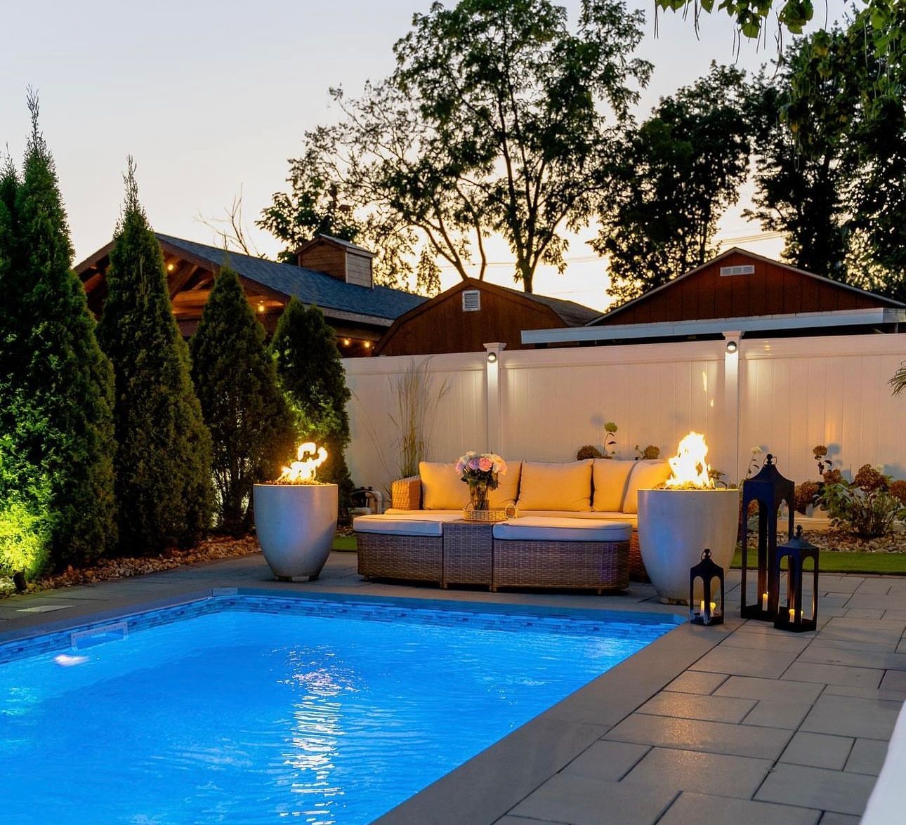 A swimming pool with a couch and lanterns in front of it