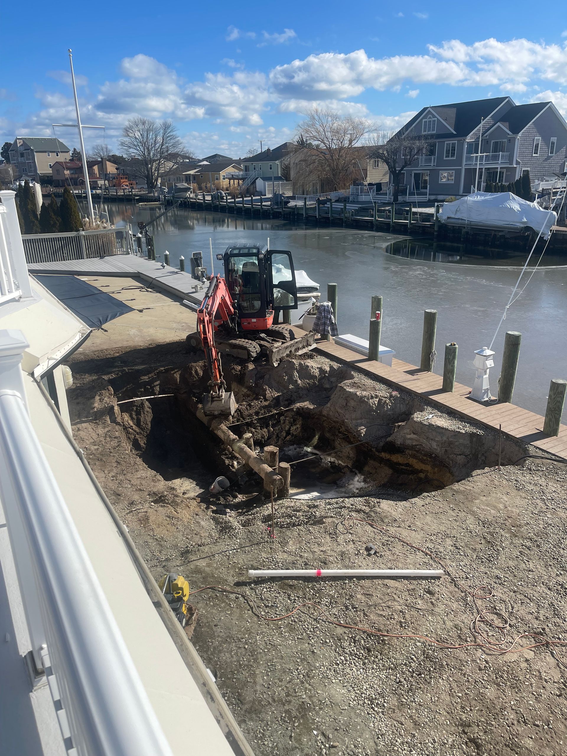 An excavator is digging a hole in the ground next to a body of water.