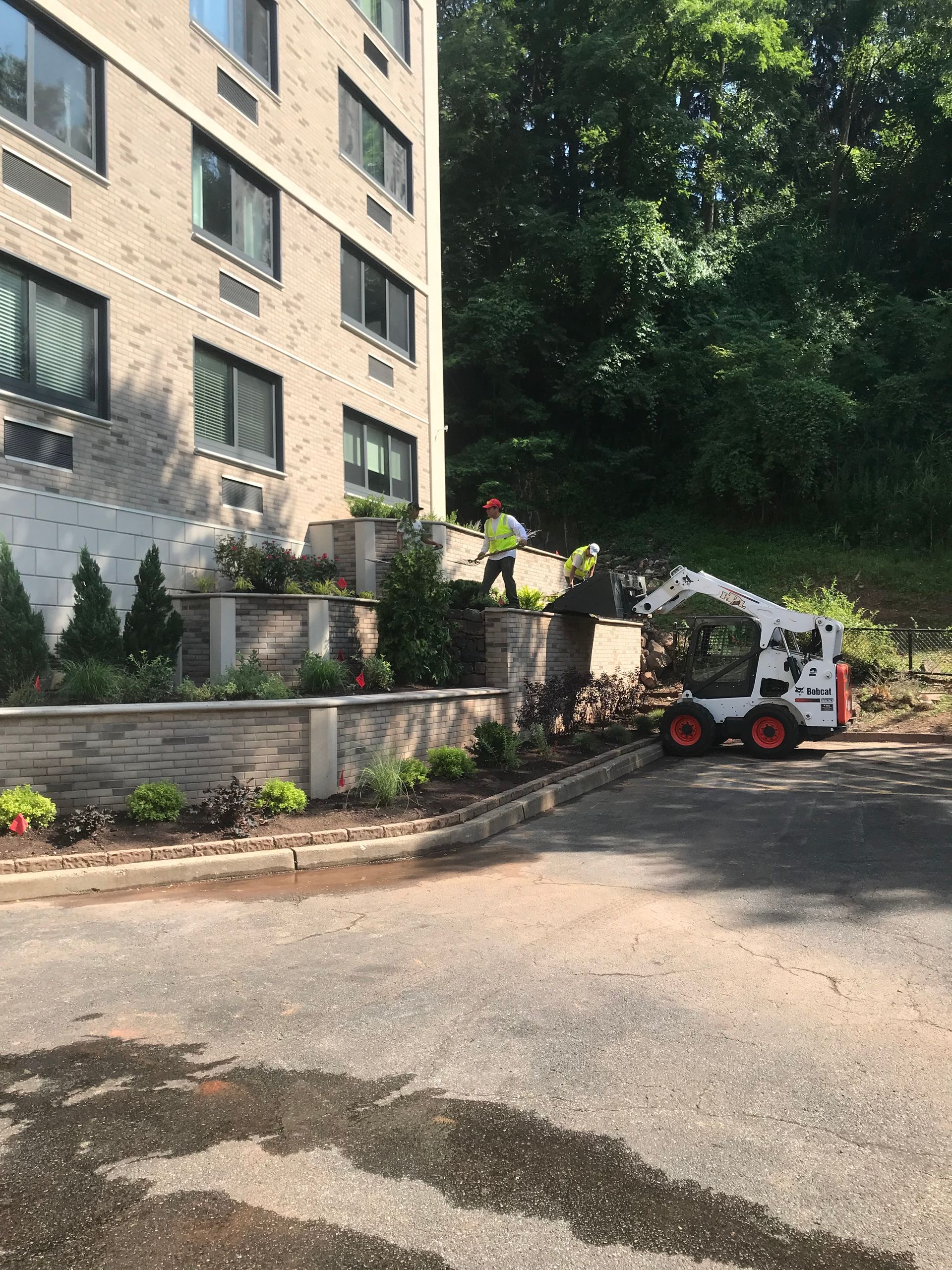 A bobcat is parked on the side of the road in front of a building.