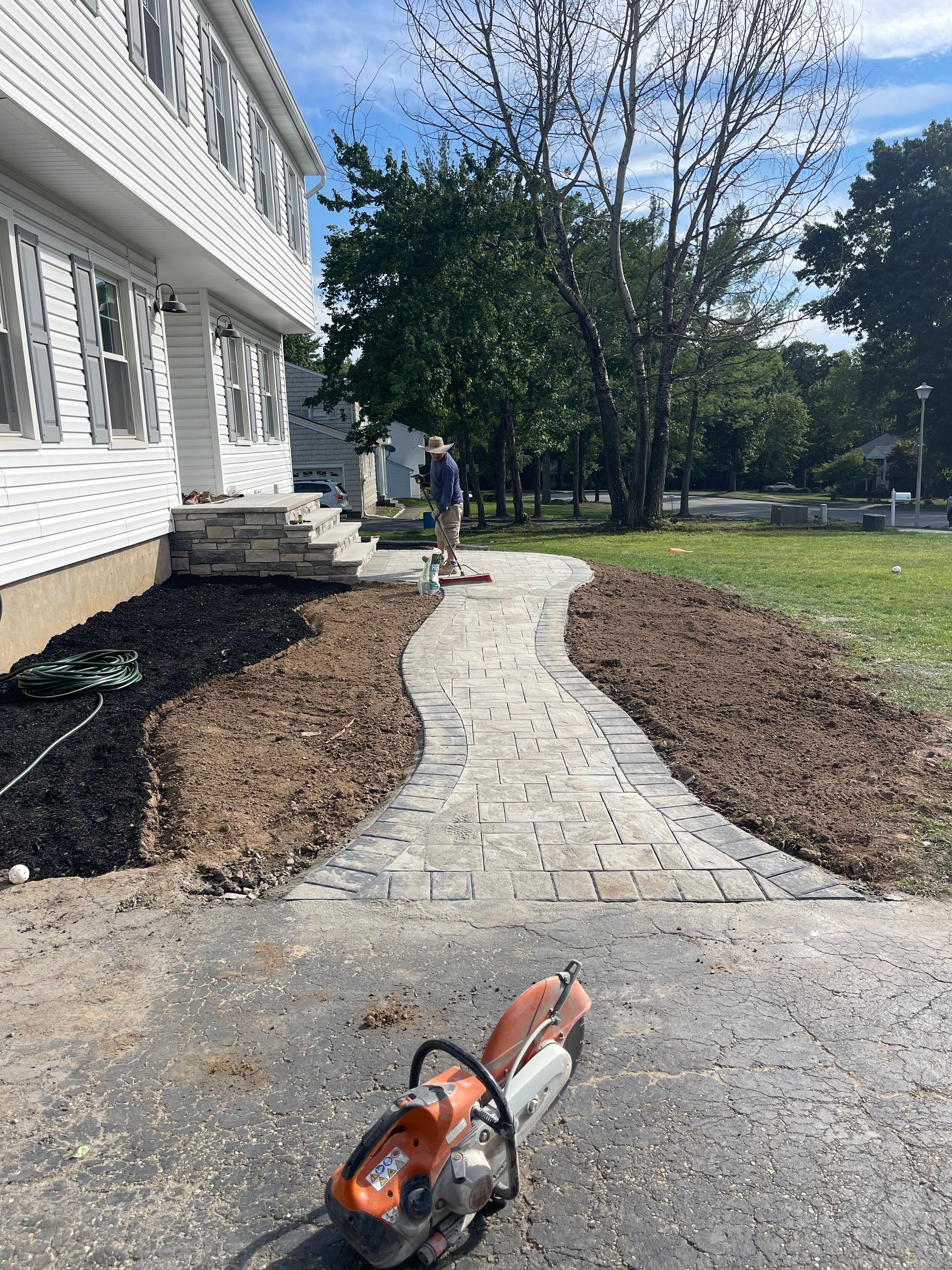 A stihl chainsaw is sitting on the sidewalk in front of a house.