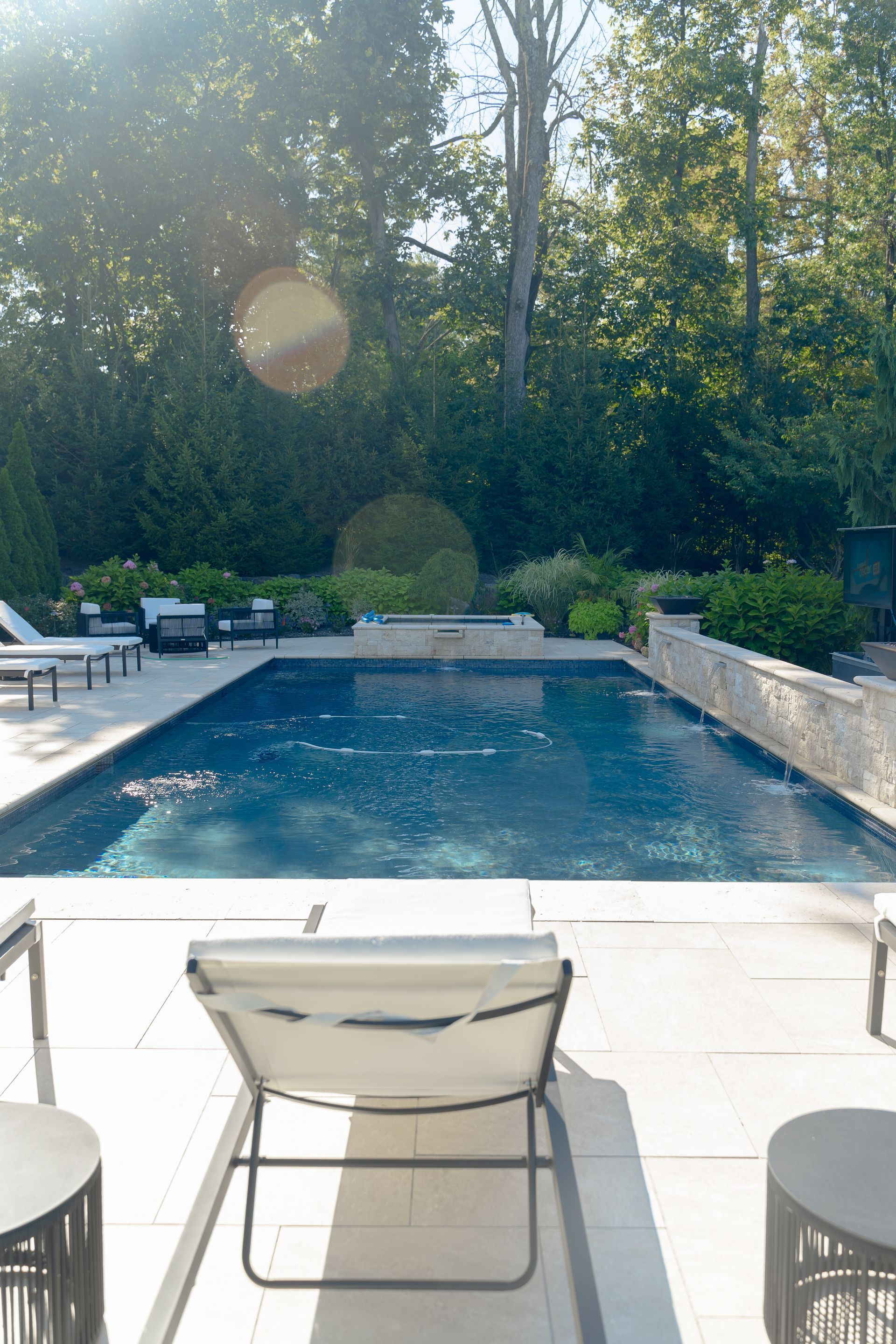 A large swimming pool surrounded by chairs and tables in a backyard.