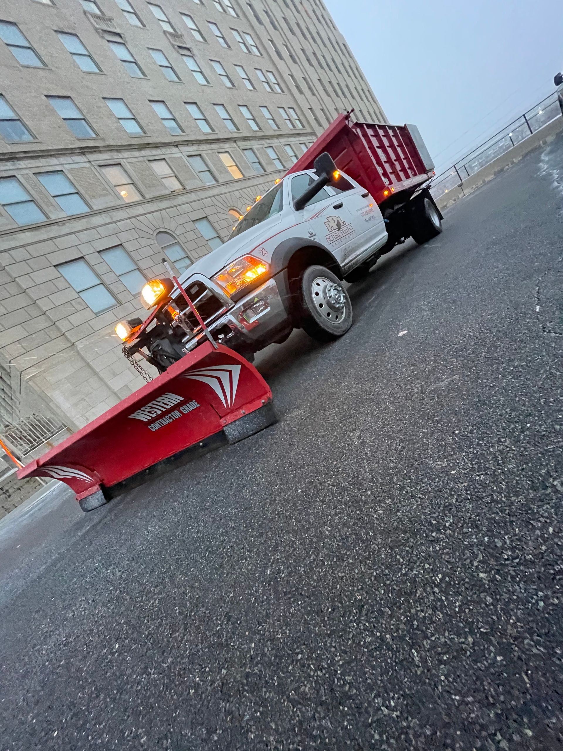 A snow plow is parked on the side of the road in front of a building.