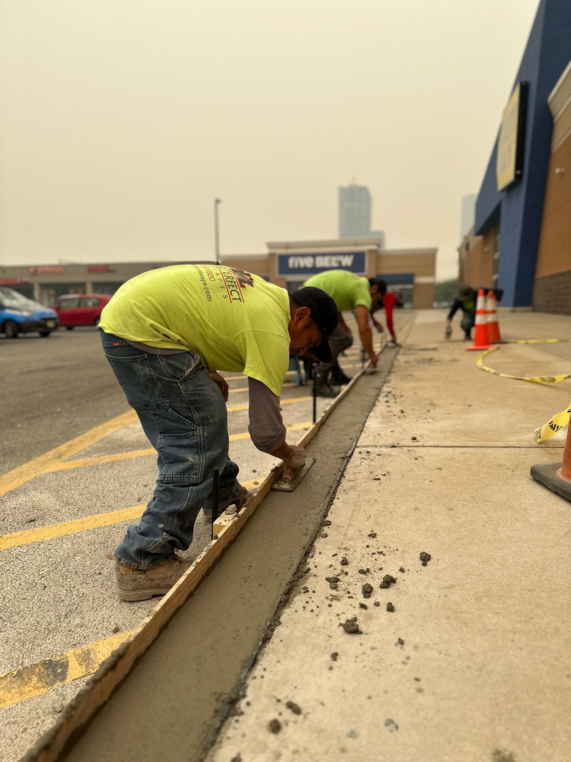 A man in a yellow shirt is working on a sidewalk