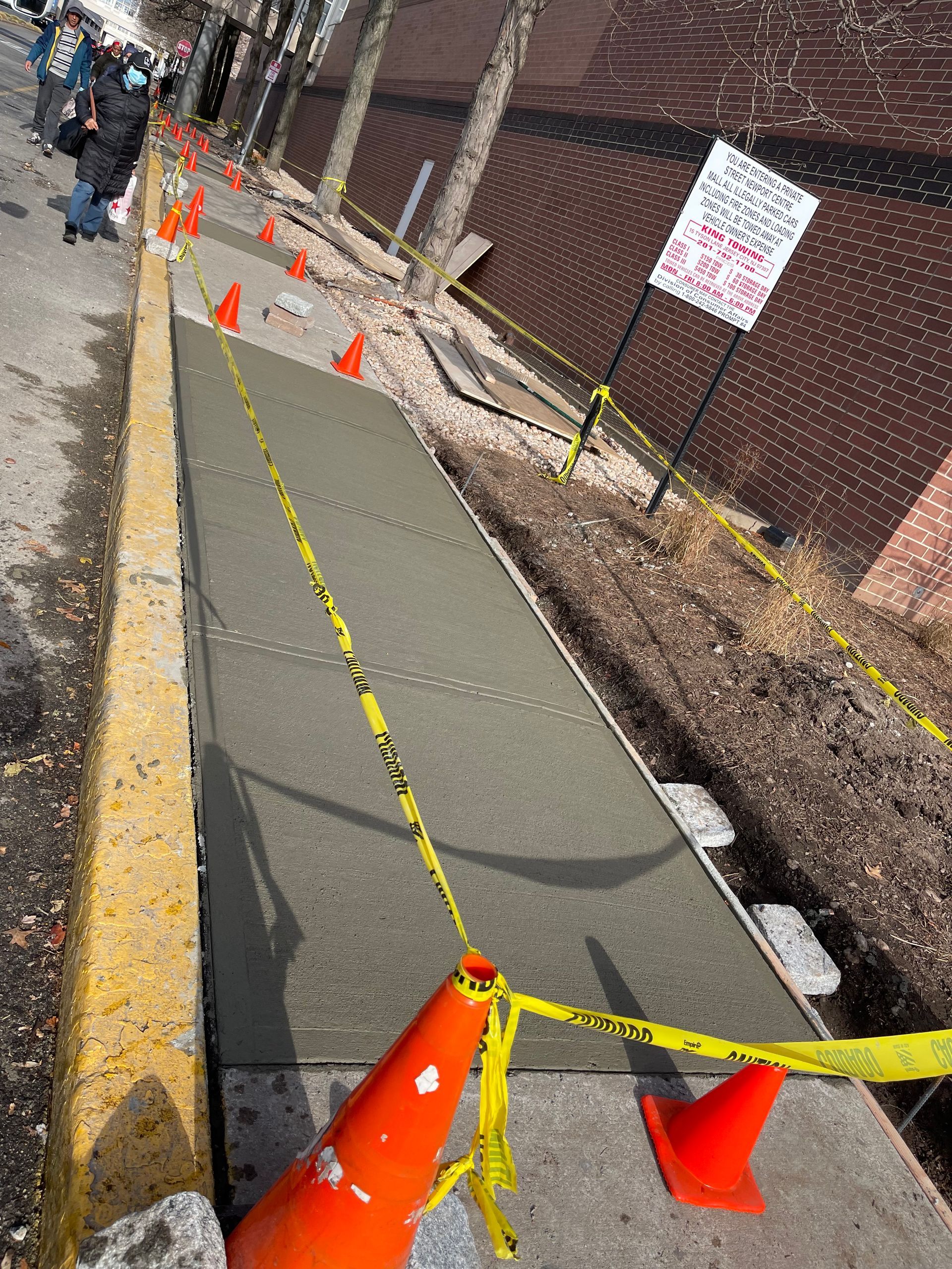 A concrete walkway is being built on the side of the road
