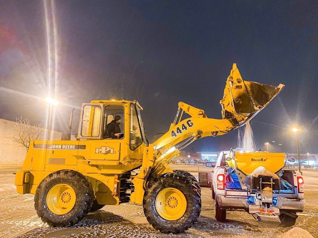 A yellow tractor is parked next to a truck at night.