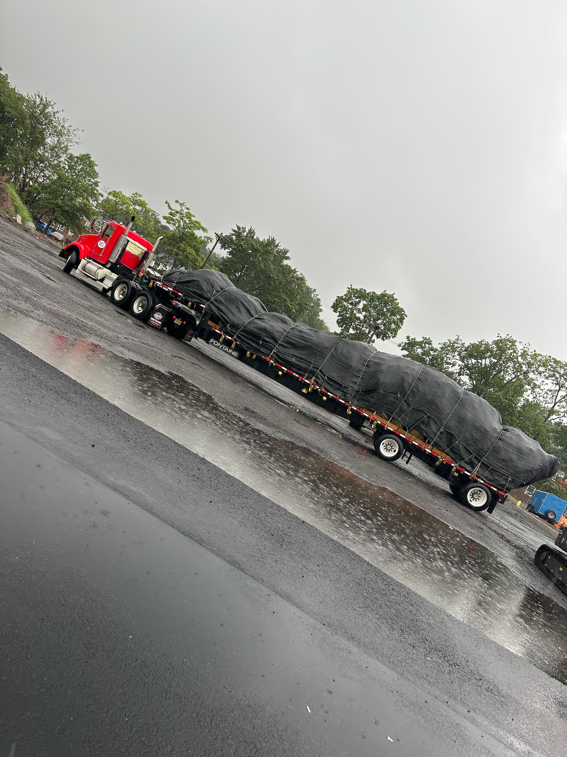 A semi truck is driving down a wet road in the rain.