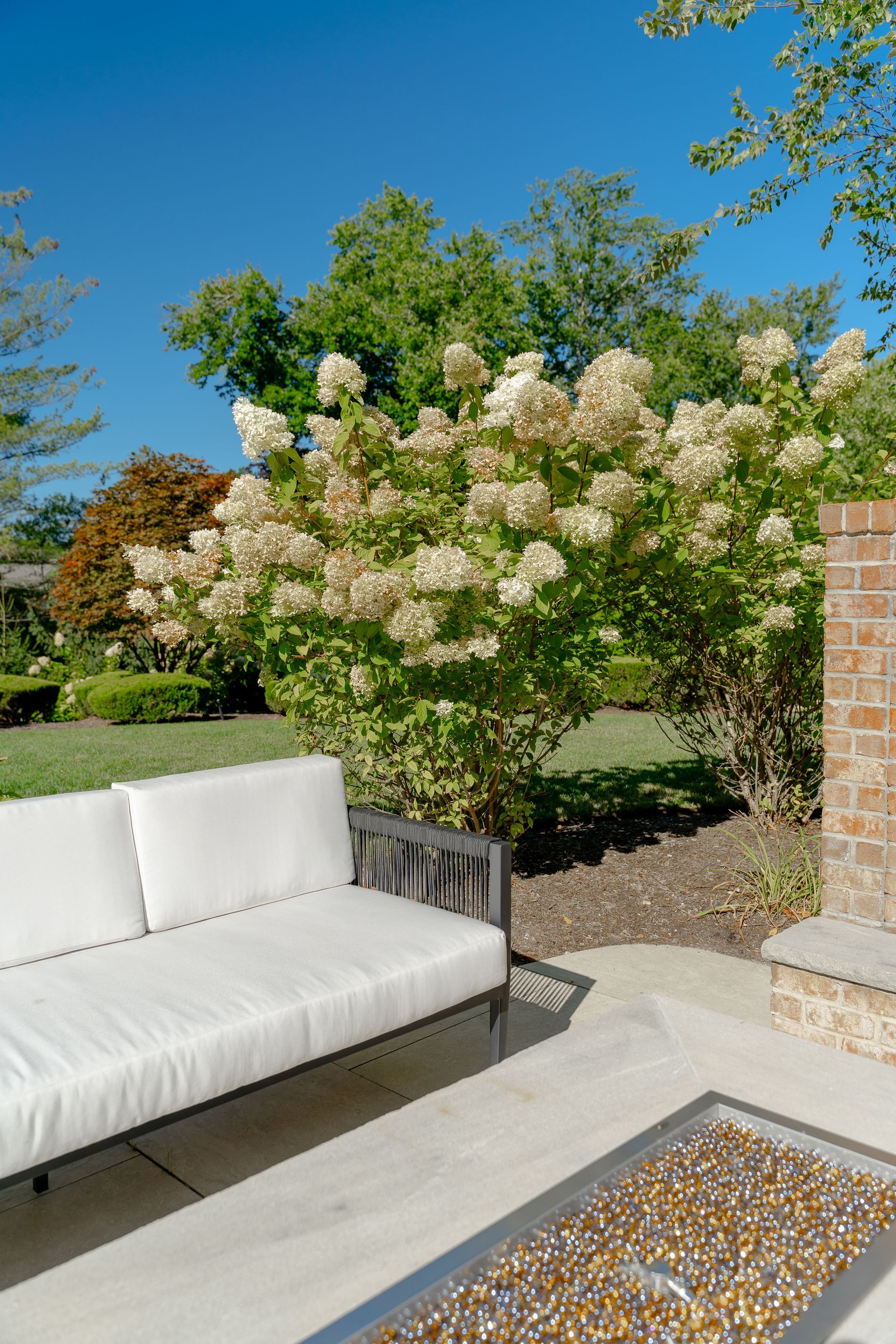 A white couch is sitting on a patio next to a fire pit.