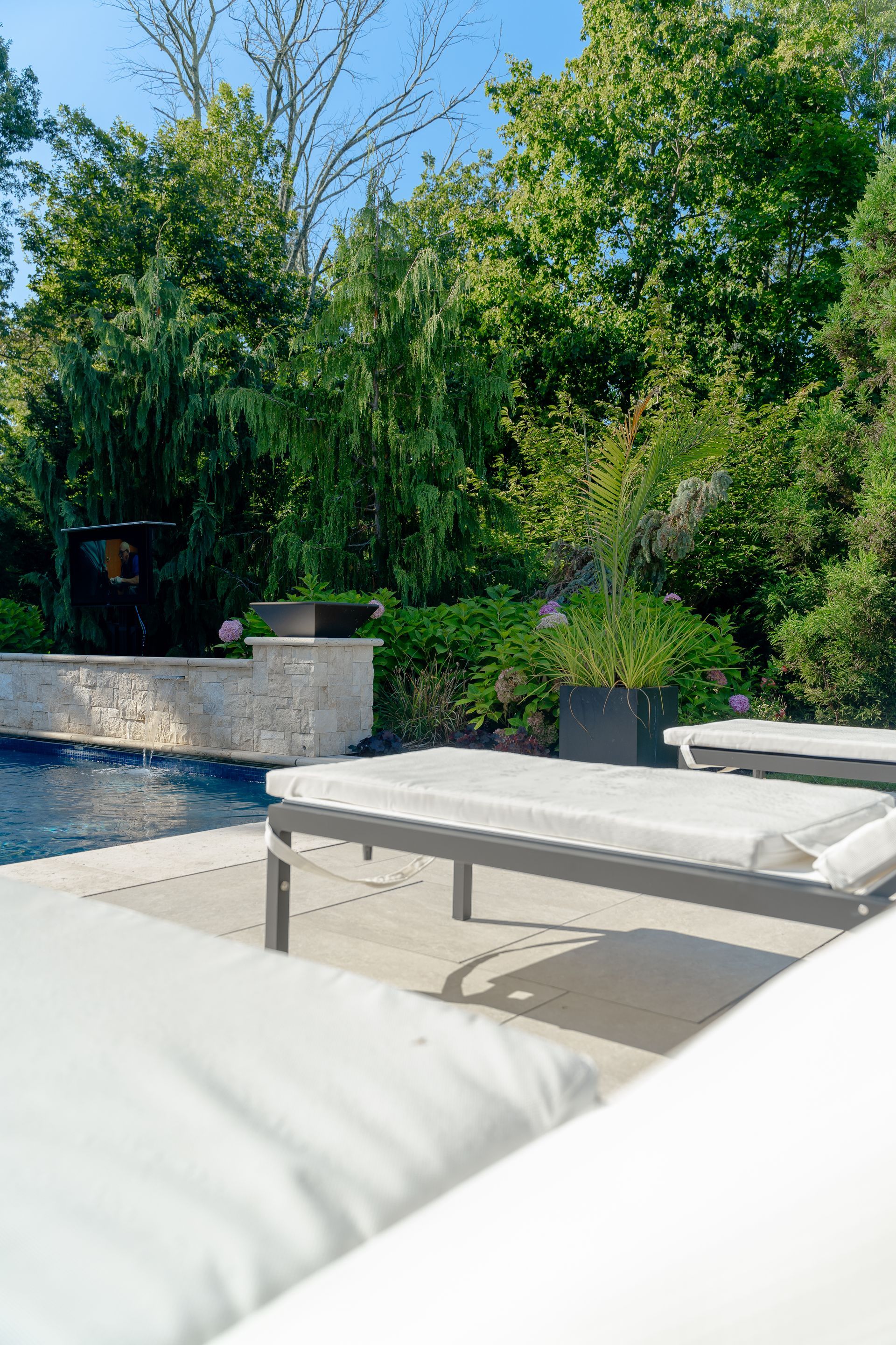 A row of lounge chairs are sitting next to a swimming pool.