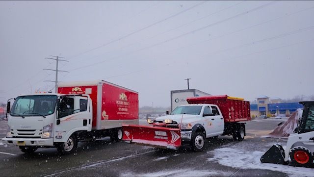 A couple of trucks parked next to each other on a snowy road.