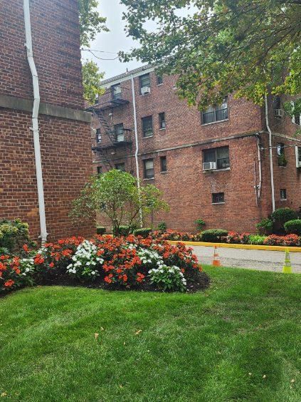 A brick building with a lot of flowers in front of it.