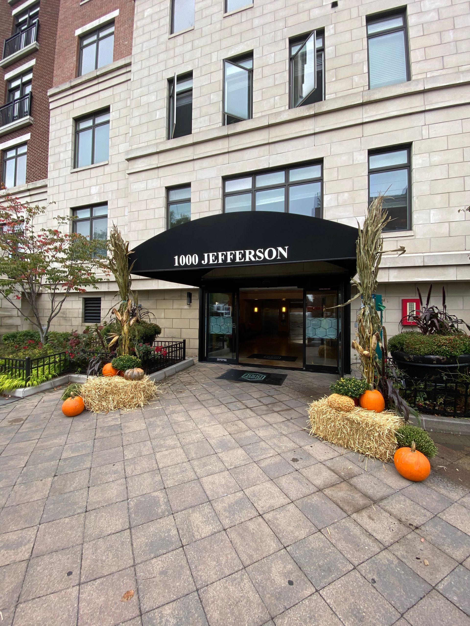 The entrance to a building with pumpkins and hay bales in front of it.