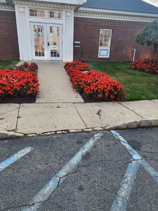 A brick building with a walkway and flowers in front of it.