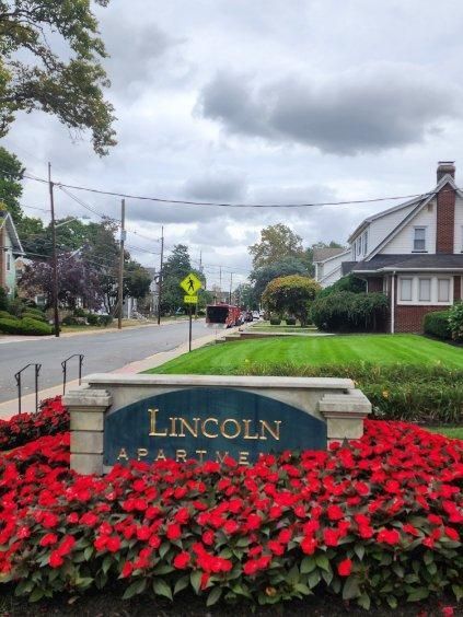 A sign for lincoln apartment is surrounded by red flowers