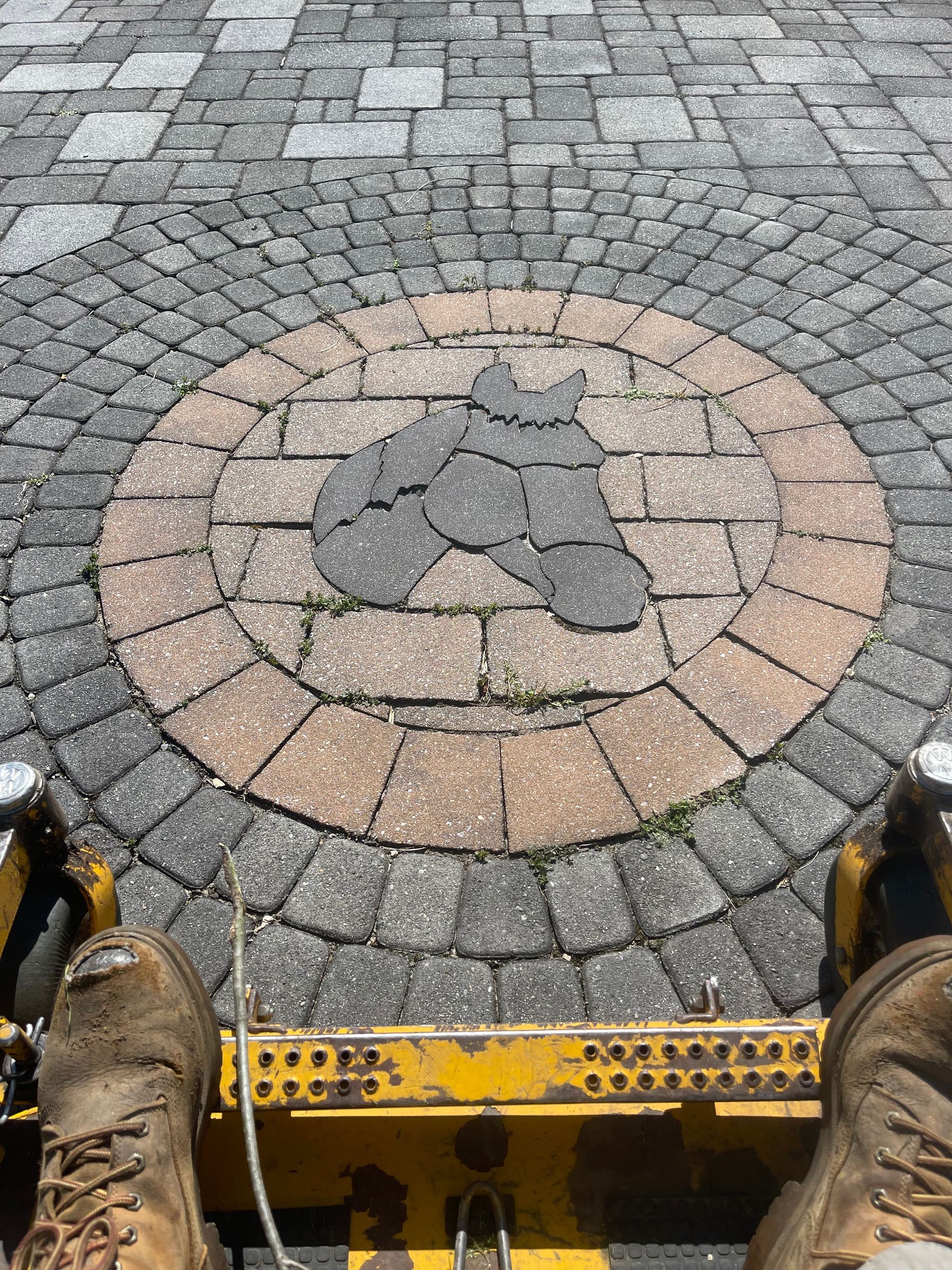 A person is sitting on a yellow scooter on a brick sidewalk.