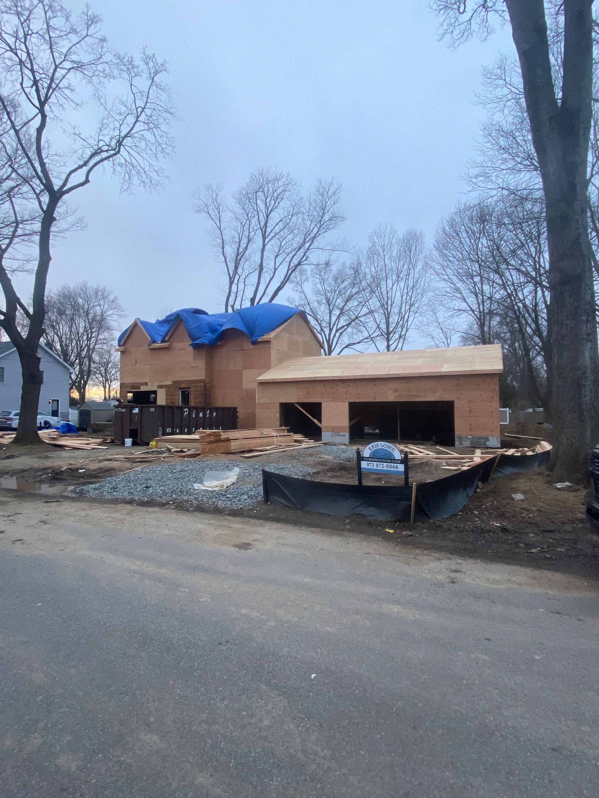 A house under construction with a blue tarp on the roof