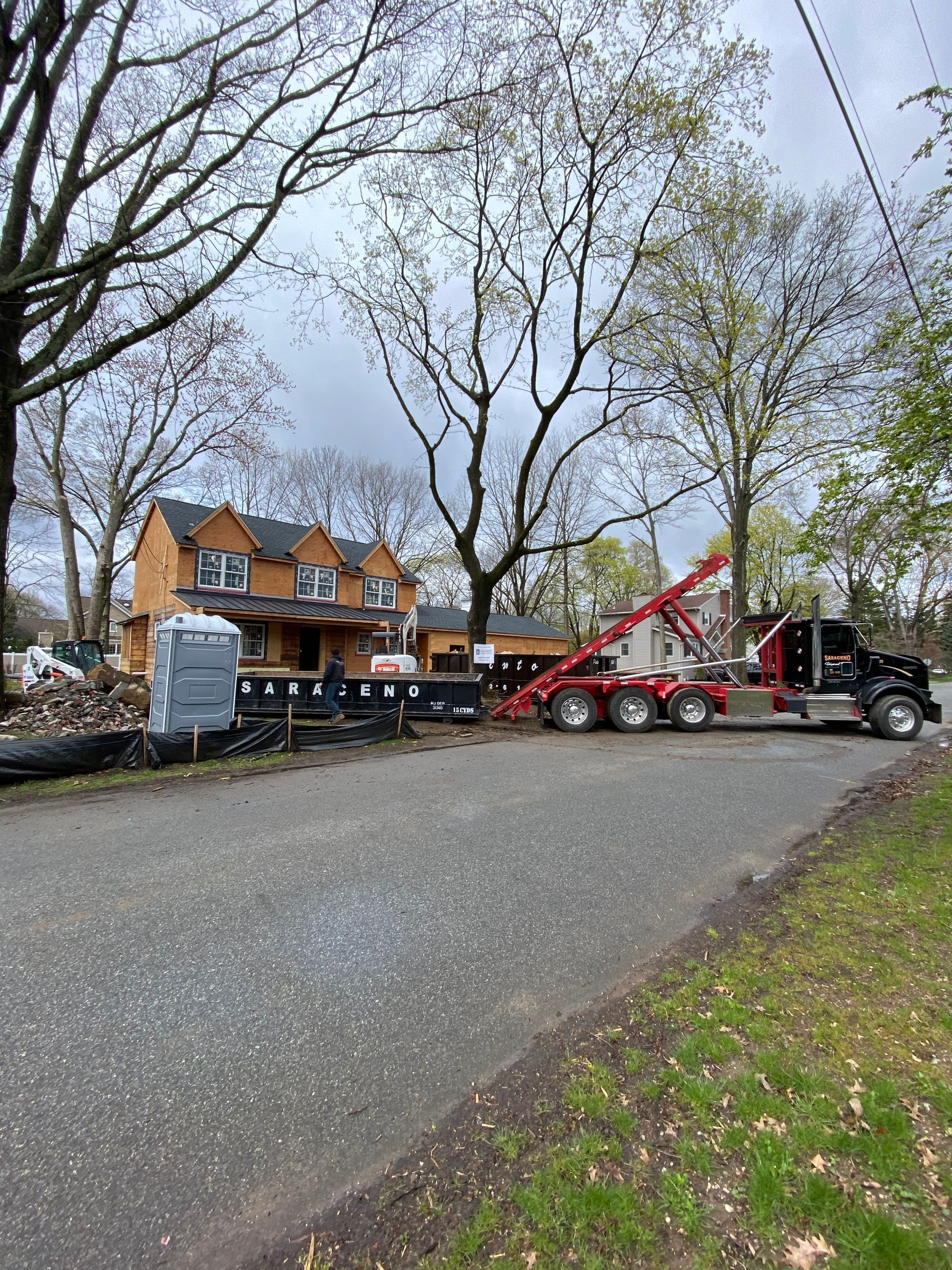 A tow truck is parked on the side of the road in front of a house under construction.