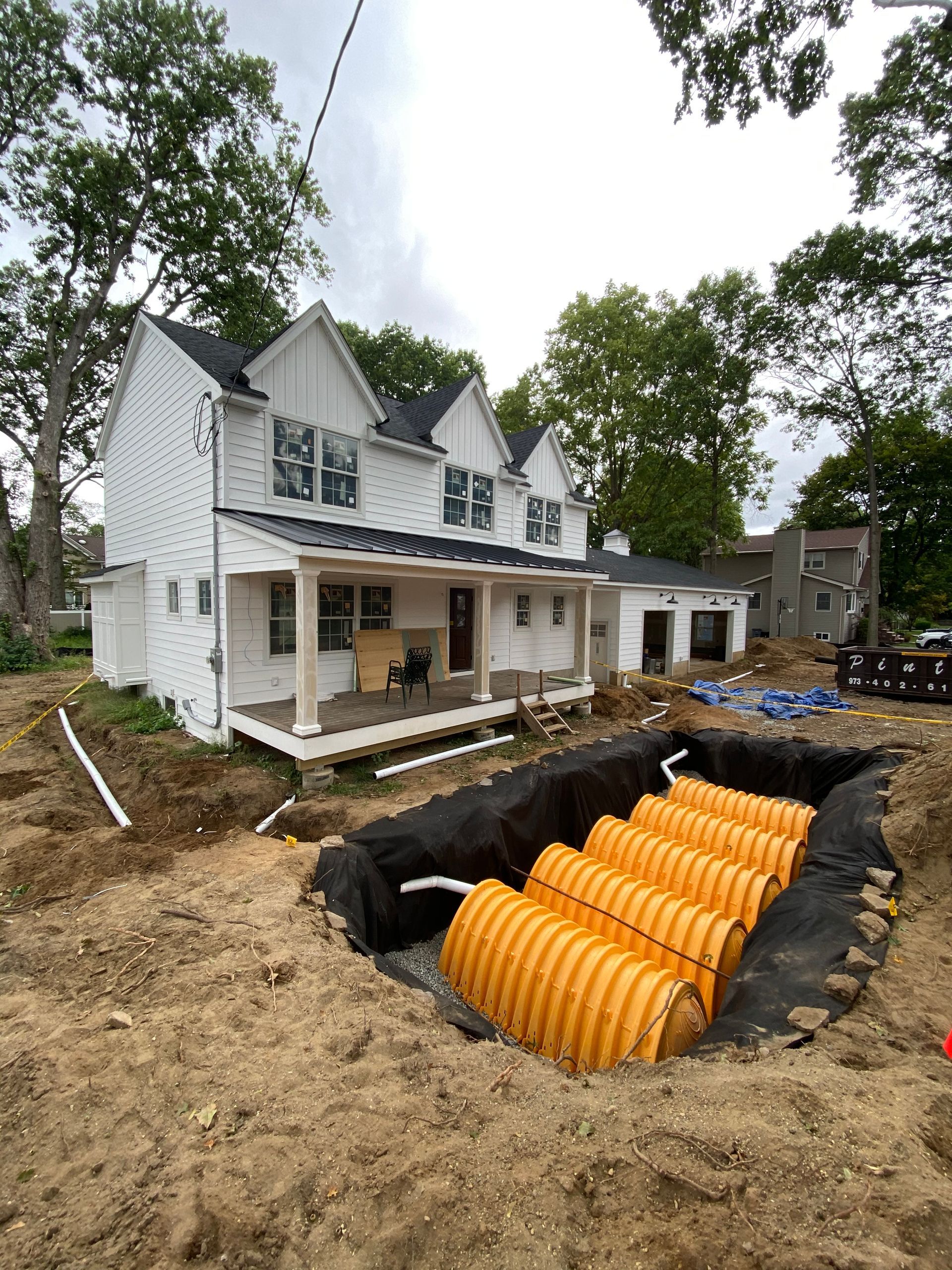 A white house with a large hole in the ground in front of it.