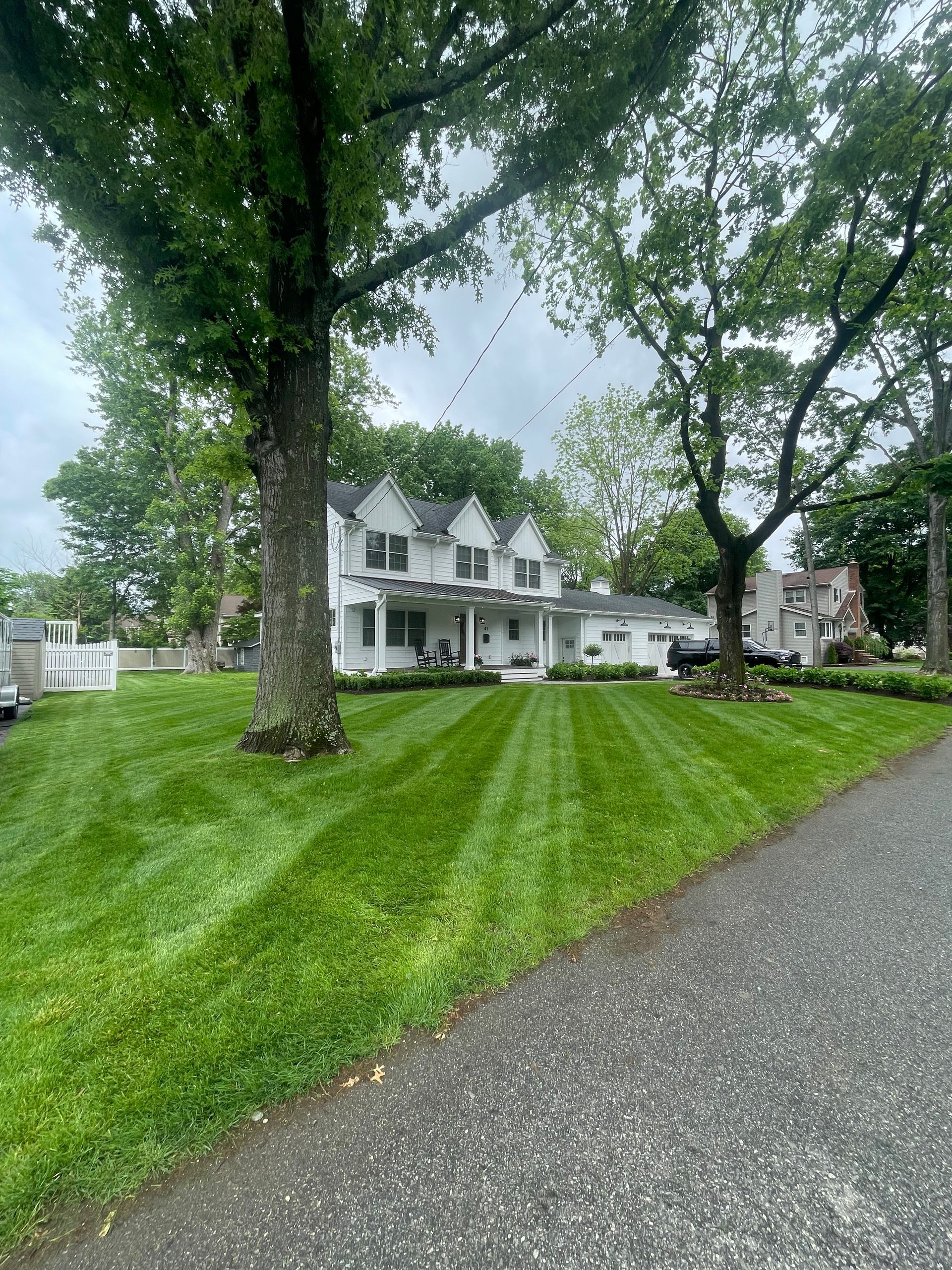 A large white house with a lush green lawn and trees in front of it.